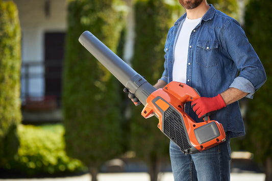 man holding a leaf blower outside