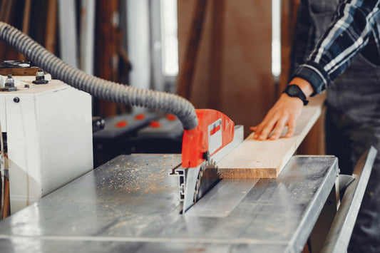 person using a benchtop table saw to cut wood