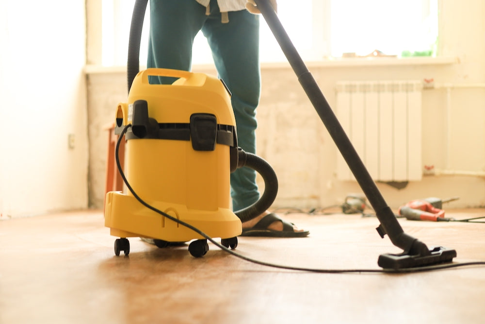 person using a wet dry vacuum on wood floor