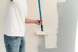 man using a paint roller to paint the wall